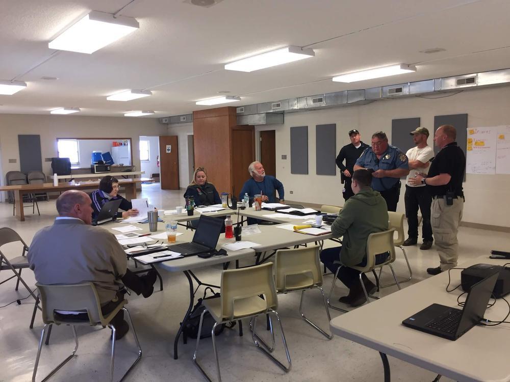 Several officers and sheriff meeting around table discussing emergency management